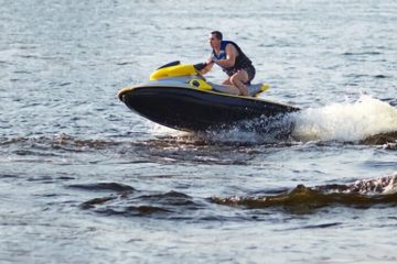 a man riding on the back of a boat in the water