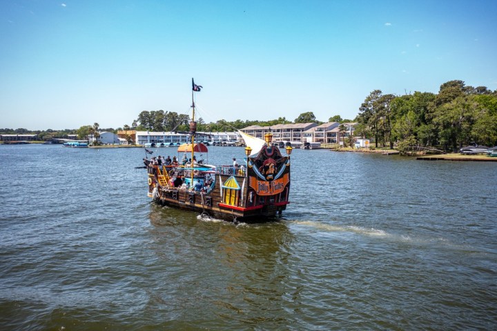 a boat floating along a river next to a body of water